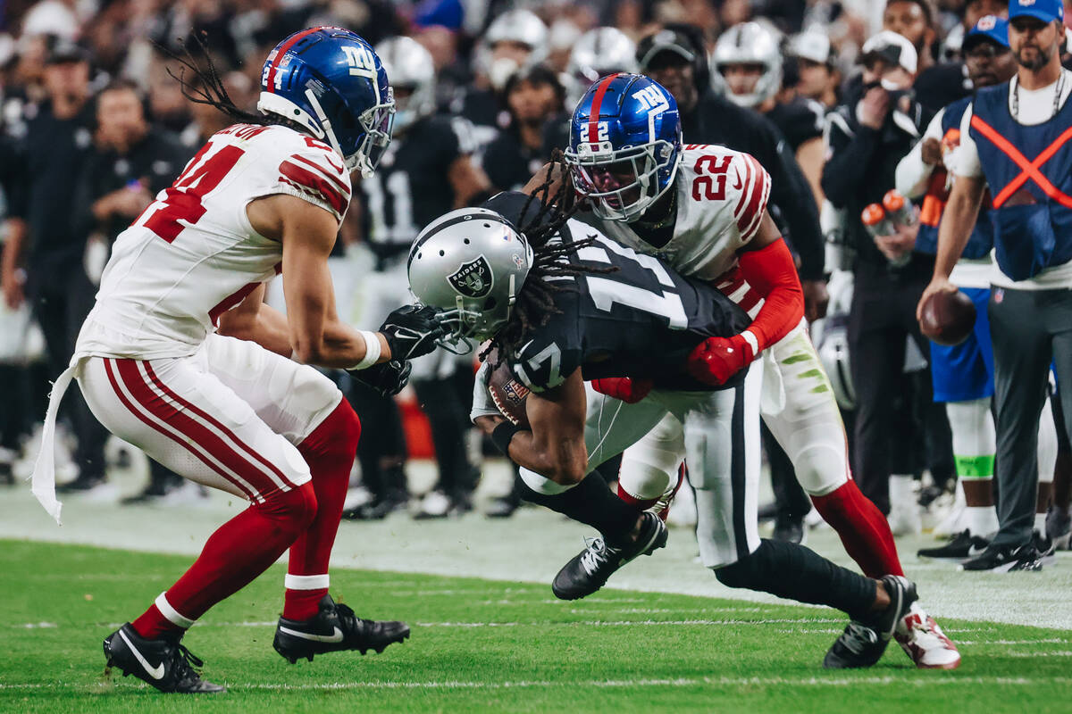 Raiders wide receiver Davante Adams (17) holds onto the ball as New York Giants cornerback Ador ...