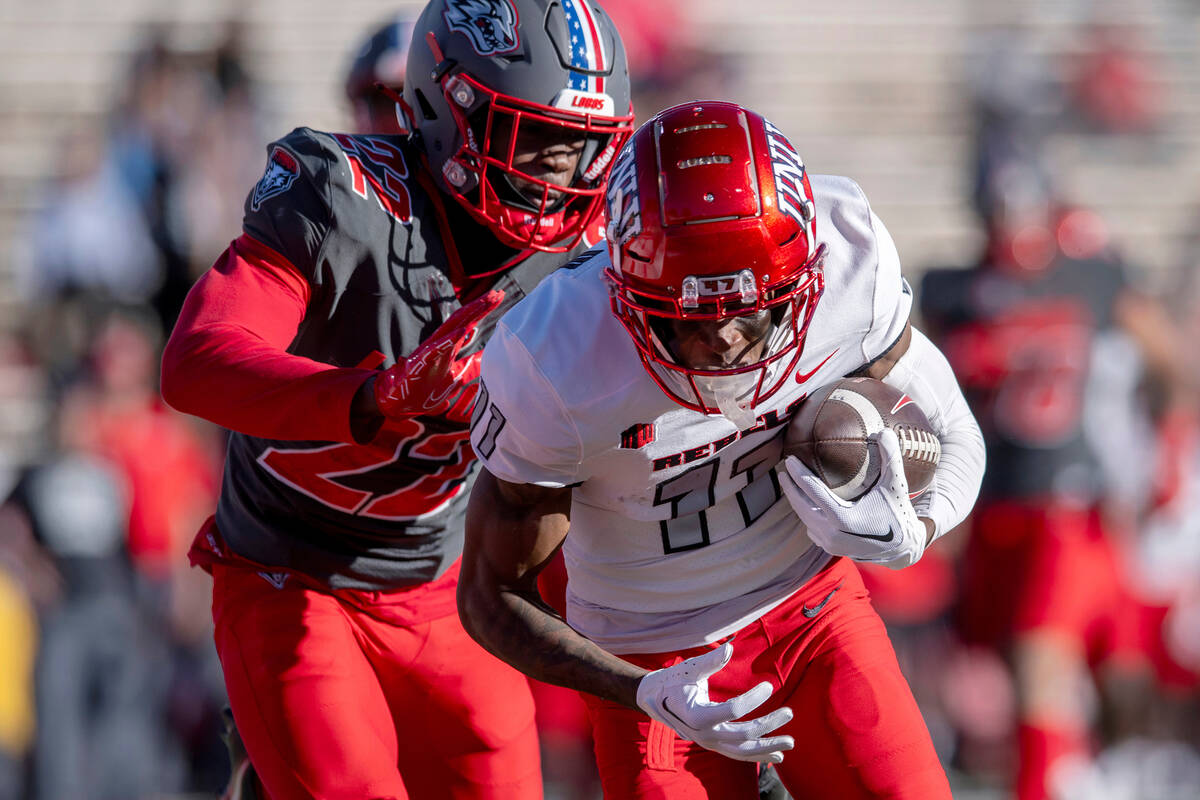 UNLV's Ricky White, right, runs a reception into the end zone in front of New Mexico's Christia ...