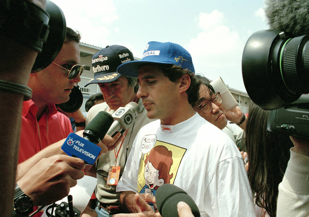 Brazilian driver Ayrton Senna is surrounded by reporters after he withdrew from the Formula One ...