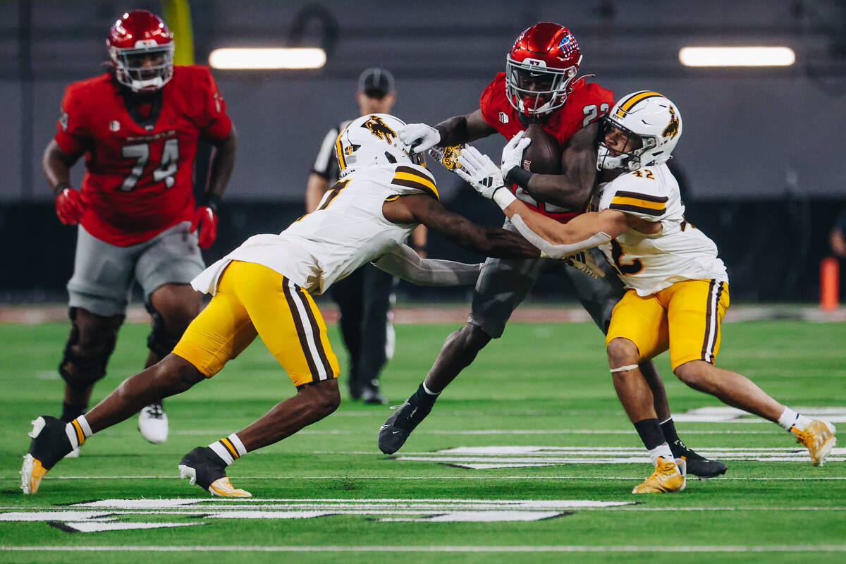 UNLV running back Jai'Den Thomas (22) carries the ball through Wyoming defenders during a game ...