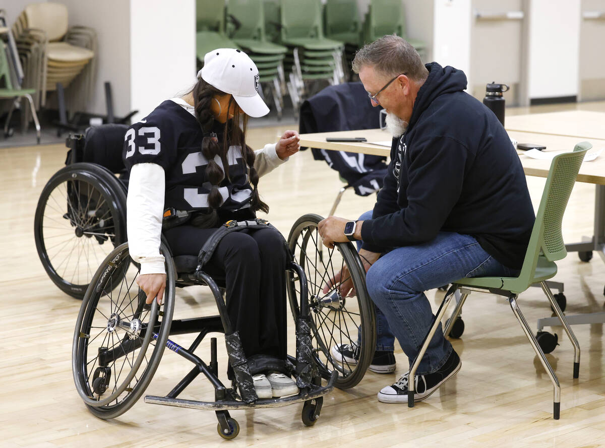 Raiders wheelchair football team head coach Bob Murray installs a wheel on Beya Tep's wheelchai ...