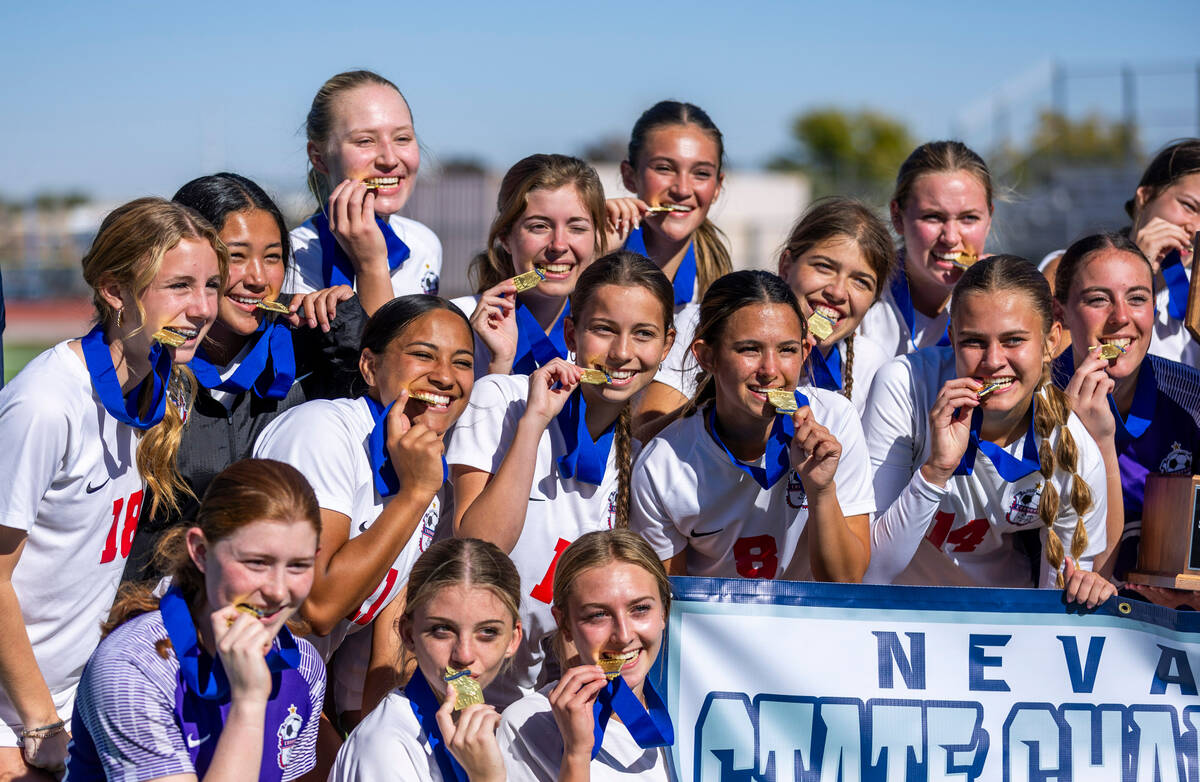 Coronado players bite their team medals as they celebrate their 2-1 win against Faith Lutheran ...