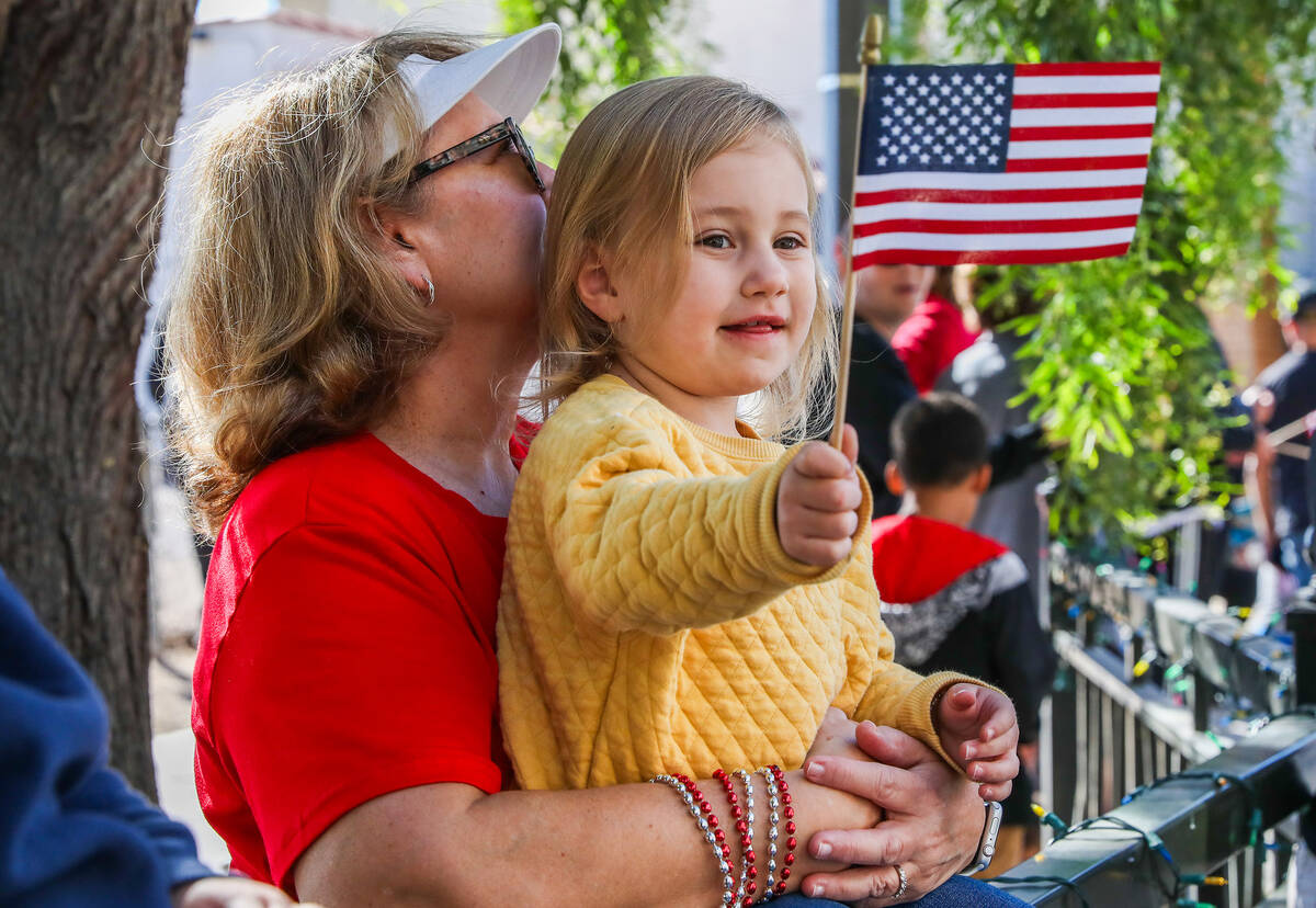Claire Graff, 3, waves an American flag while Susan Graff holds her up during the annual Vetera ...