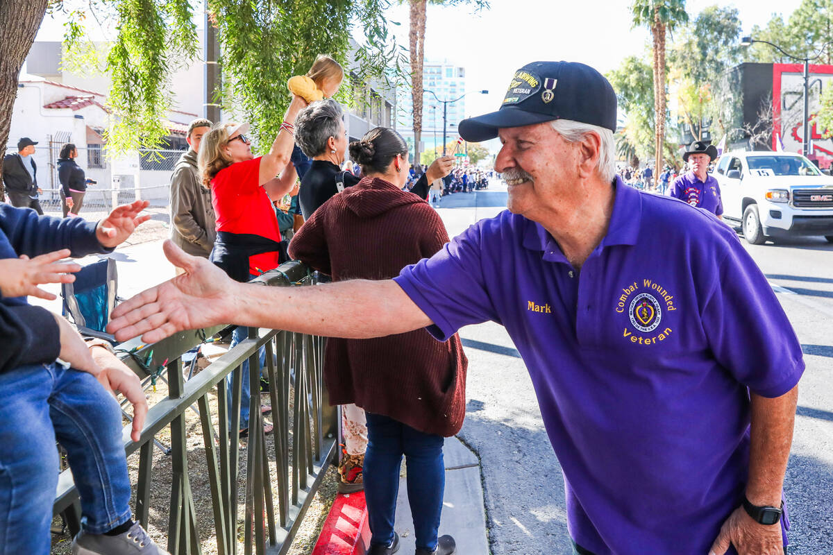 Mark, a combat wounded Veteran, reaches out to the crowd during the annual Veterans Day parade ...