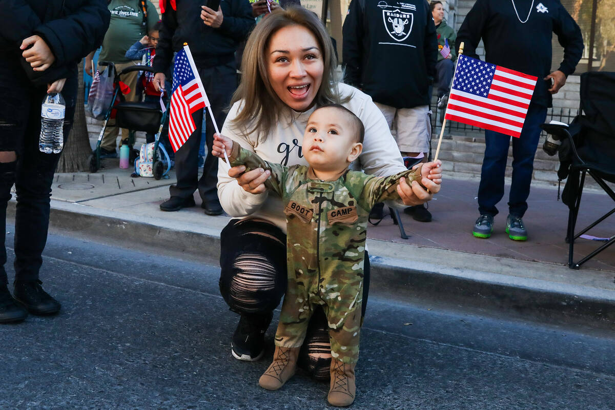 Selena Martinez and Benny Martinez, 1, wave to their son and brother who is marching with the C ...