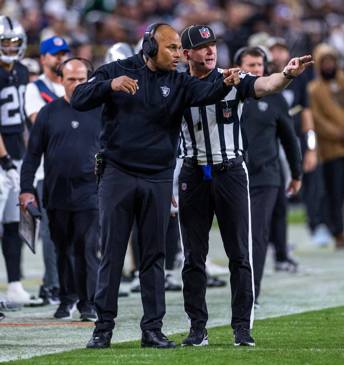 Raiders head coach Antonio Pierce decides on a penalty call with a referee against the New York ...