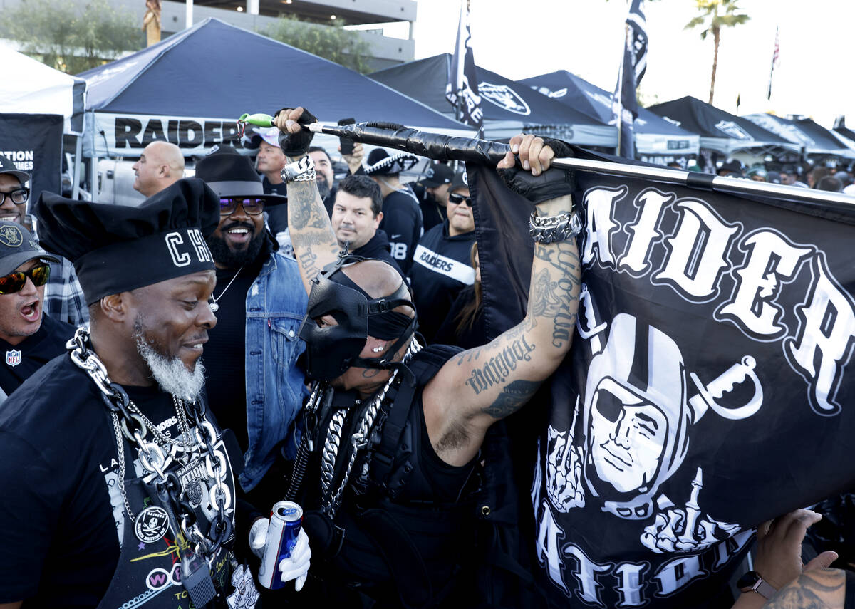 Raiders fan Raiders-Pearl, right, waves the Raiders flag as he tailgates outside Allegiant Stad ...