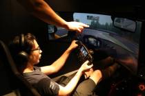 A McLaren simulator coach helps Joseph Launi, visiting from Toronto, Canada for the Formula 1 r ...