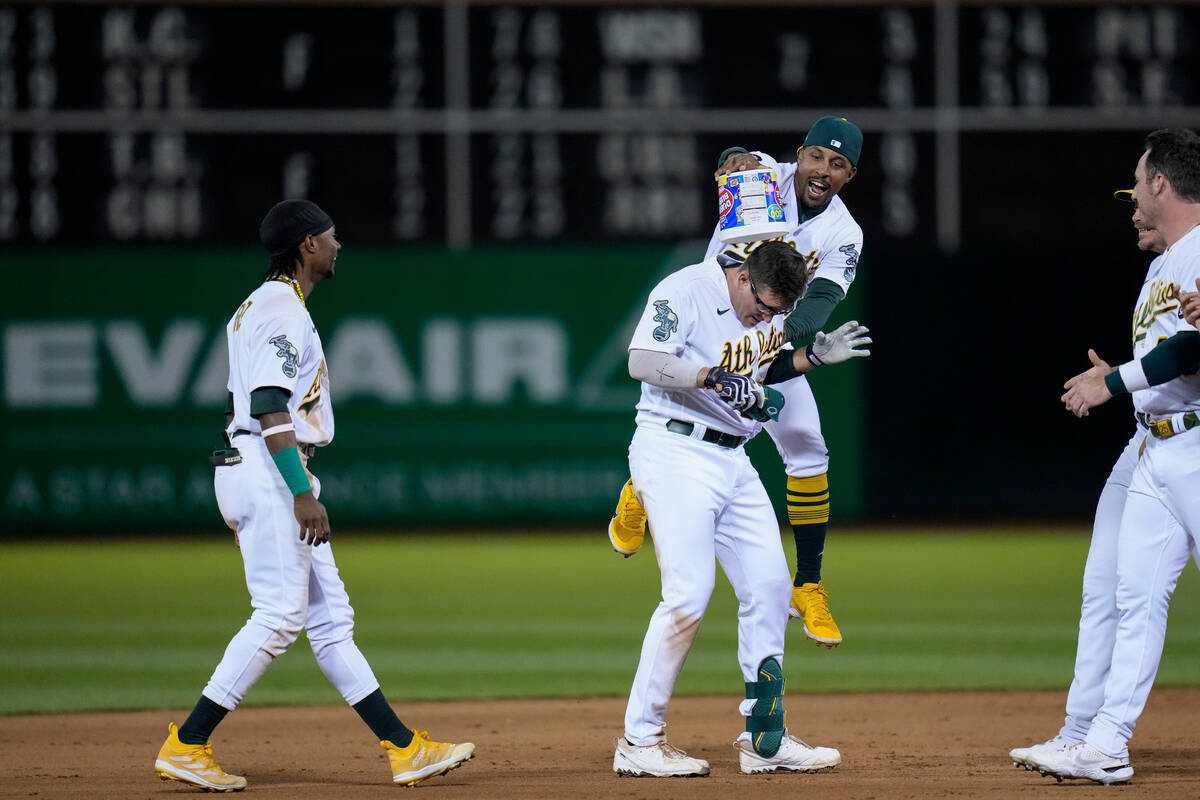 Oakland Athletics' Jonah Bride, center, celebrates with teammates after reaching first on a gro ...