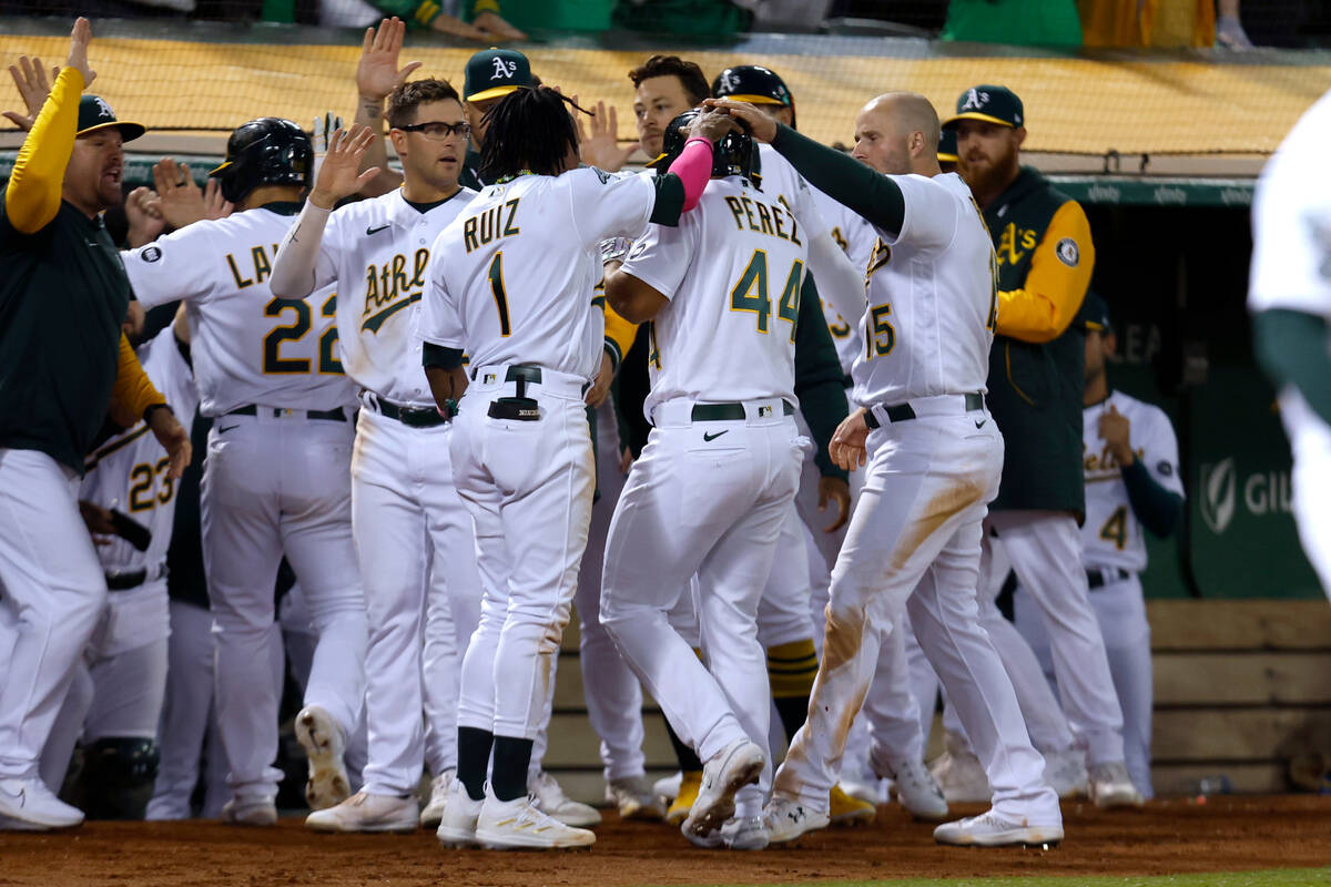 Oakland Athletics' Carlos Perez (44) is congratulated by teammates after driving in a run with ...