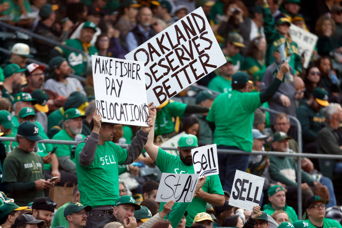 Fans hold signs inside of the Oakland Coliseum to protest the Oakland Athletics' planned move t ...