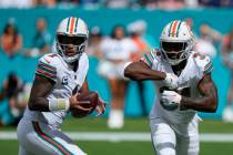 Miami Dolphins quarterback Tua Tagovailoa (1) looks to make a play as Miami Dolphins running ba ...