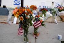 Flowers and flags are left at a makeshift shrine placed at the scene of a Sunday confrontation ...