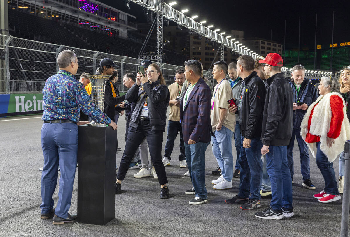 Invited guests get time with the winner's trophy as they tour pit lane before the practice sess ...