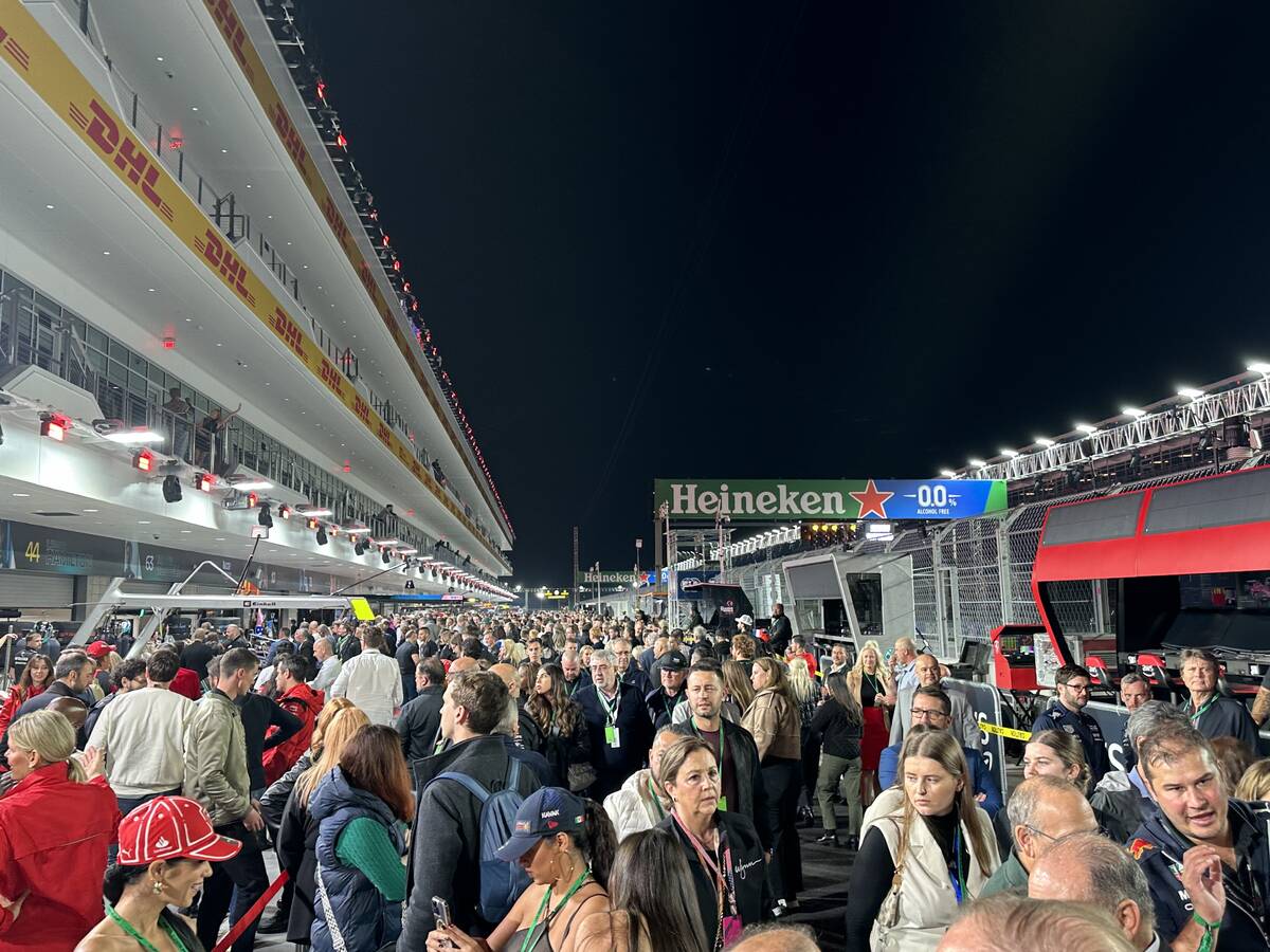 Race fans with suite-level access mill about the pit lane during the canceled practice session ...