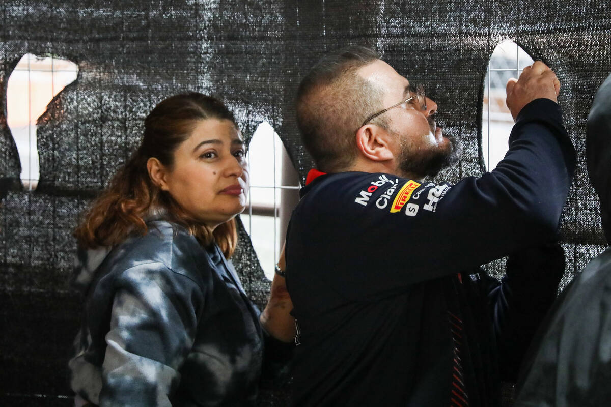 Fans cut holes into fence netting to watch the Formula 1 Las Vegas Grand Prix race on Saturday, ...