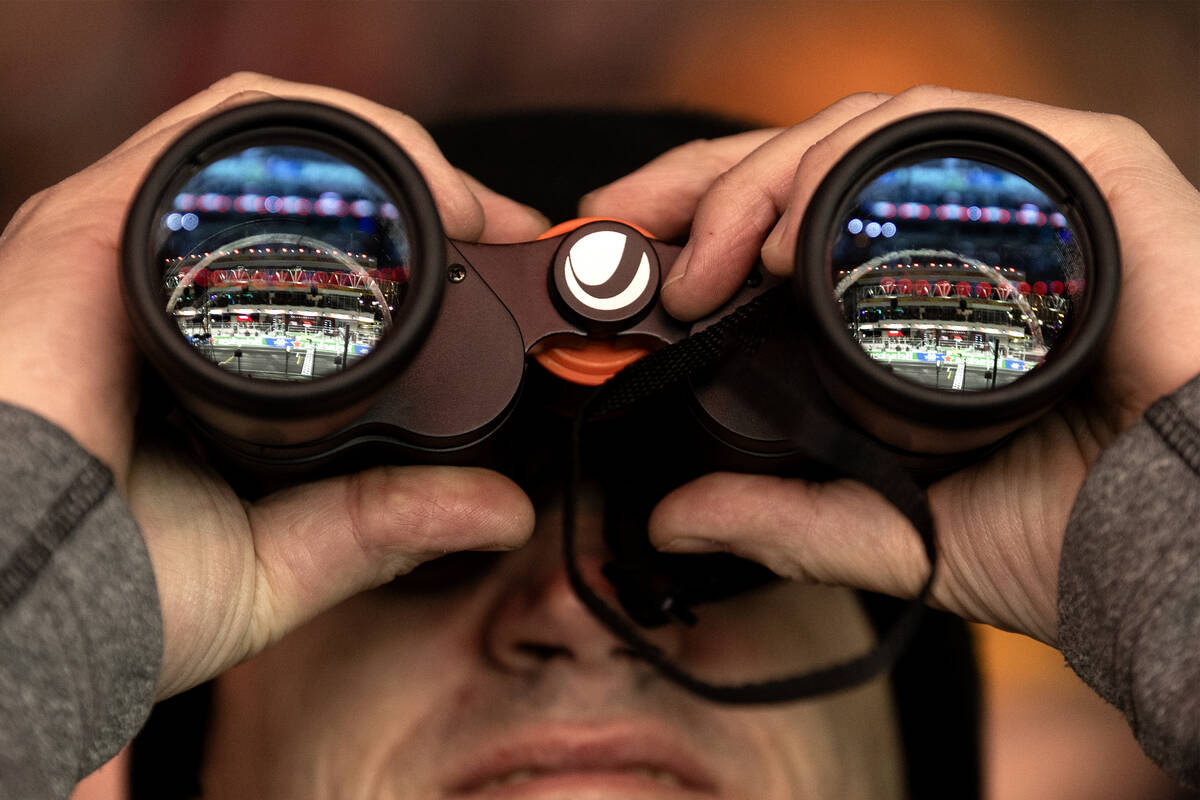 A fan uses binoculars to view the Formula One Las Vegas Grand Prix auto race on Sunday, Nov. 19 ...