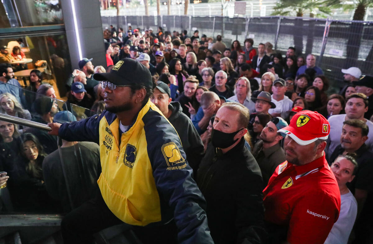 A security guard holds back a hard of people prior to the final Formula 1 Las Vegas Grand Prix ...