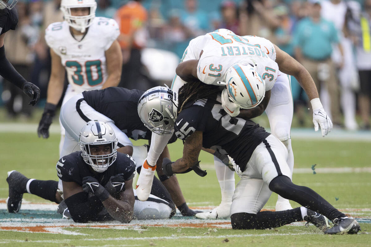 Raiders linebacker Divine Deablo (5) looks on as safety Tre'von Moehrig (25) tackles Miami Dolp ...