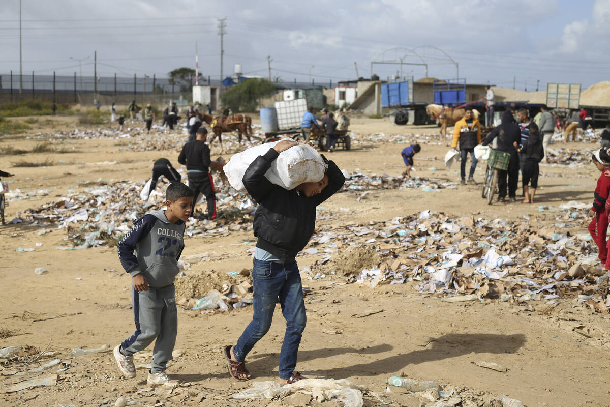 A Palestinian boy carries water looted from the humanitarian aid trucks during the ongoing Isra ...