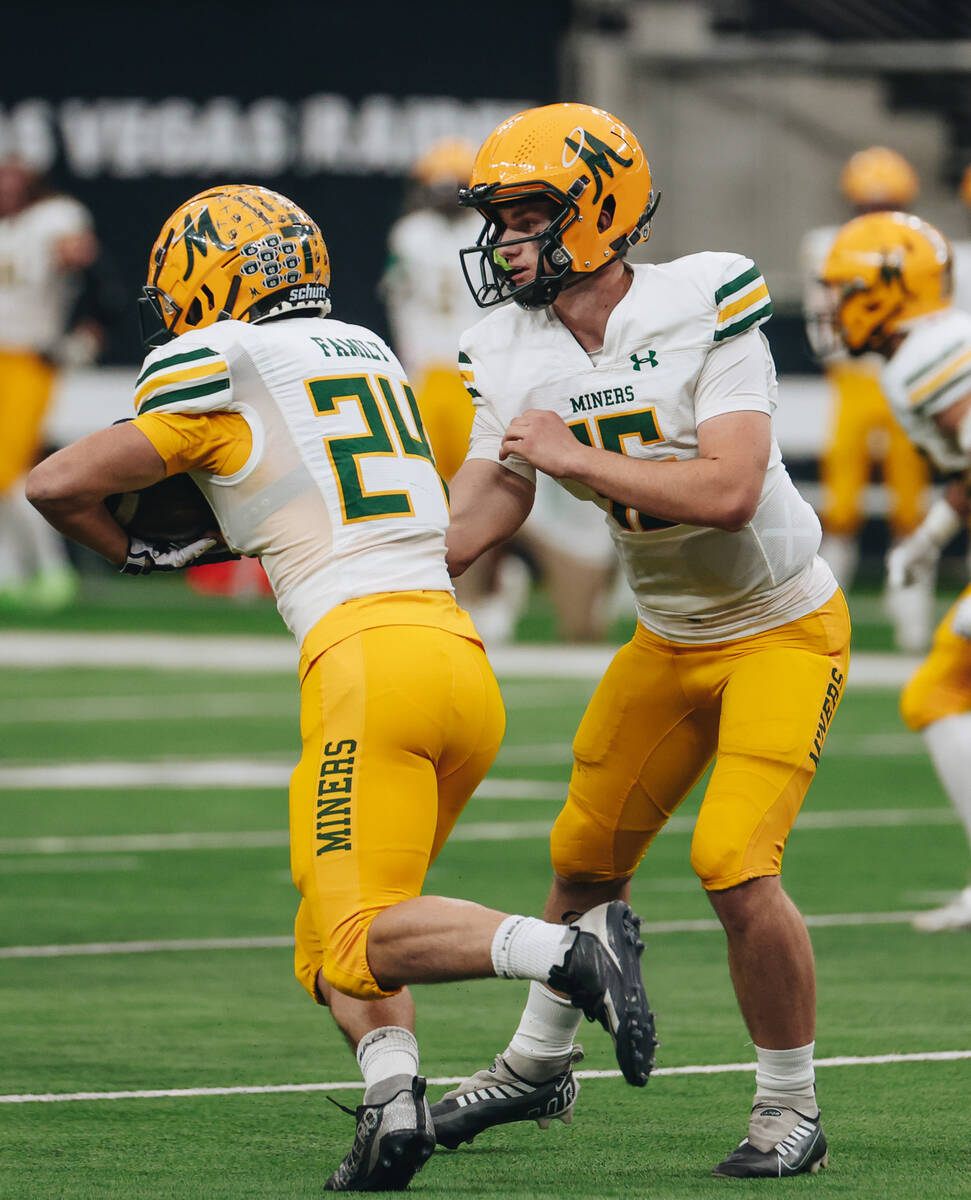 Bishop Manogue quarterback Philip Jacobs (16) passes the ball off to running back Cody Fleischm ...