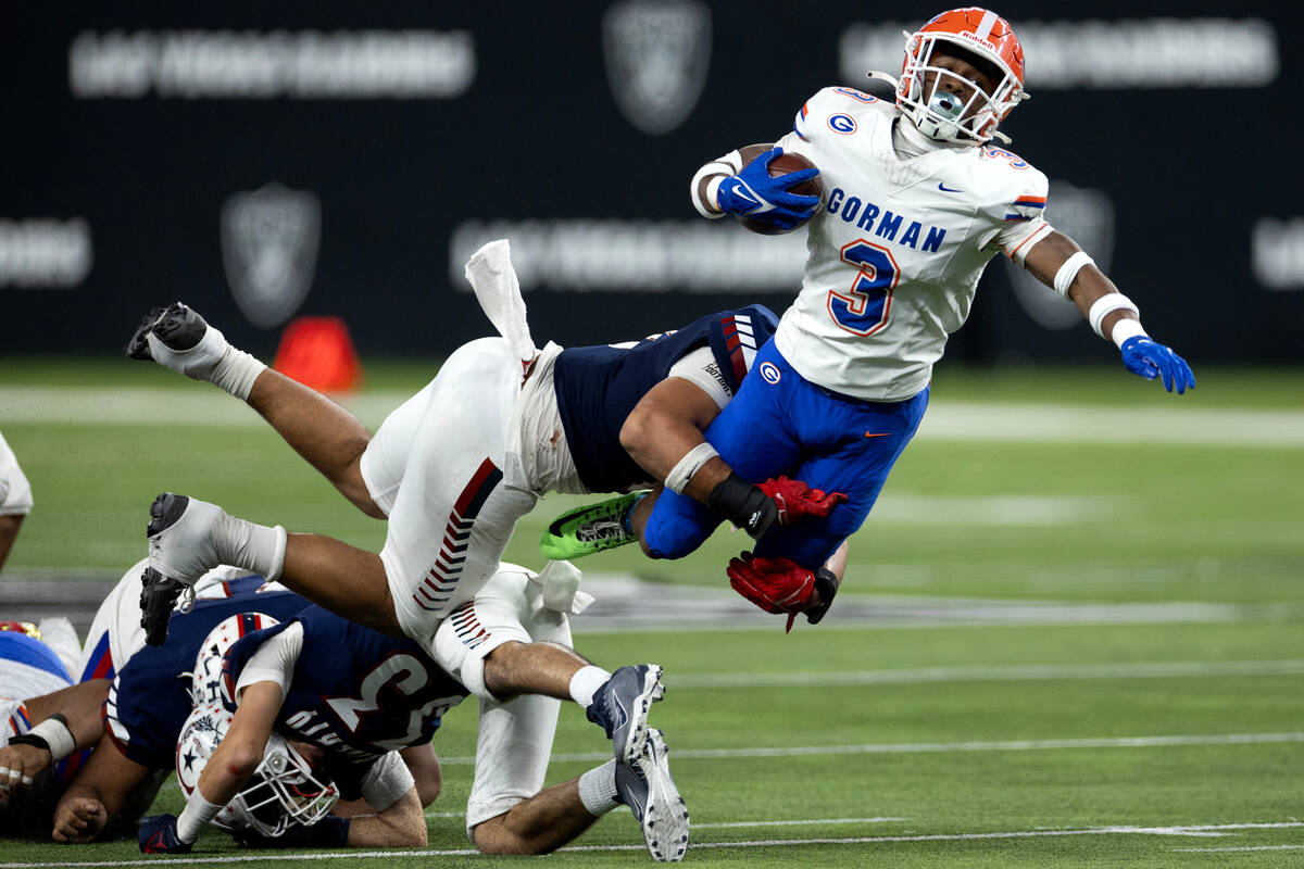 Bishop Gorman running back Devon Rice (3) dives through a tackle by Liberty’s Louden Wil ...