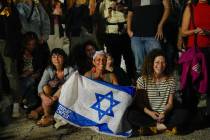 People react as they hear the news of the release of 13 Israeli hostages held by Hamas in the G ...