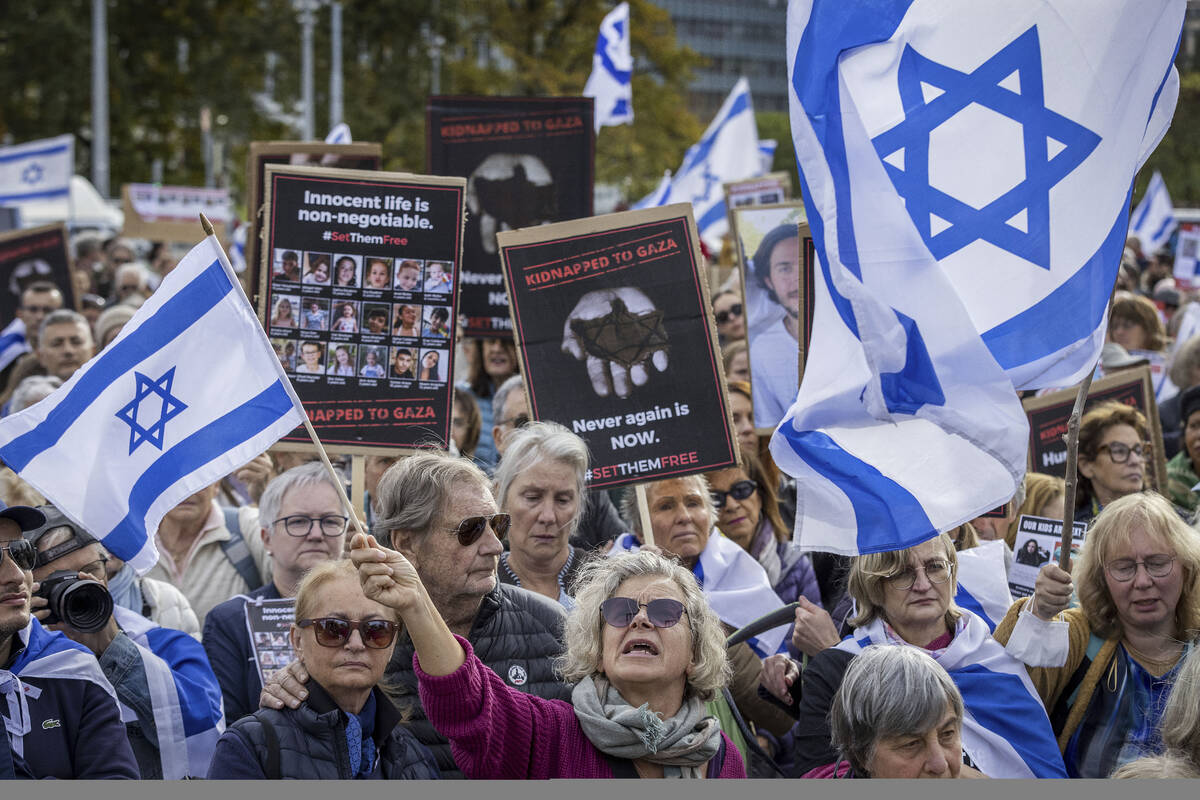 FILE - Protesters hold banners with hostages' pictures and Israel flags during a gathering next ...