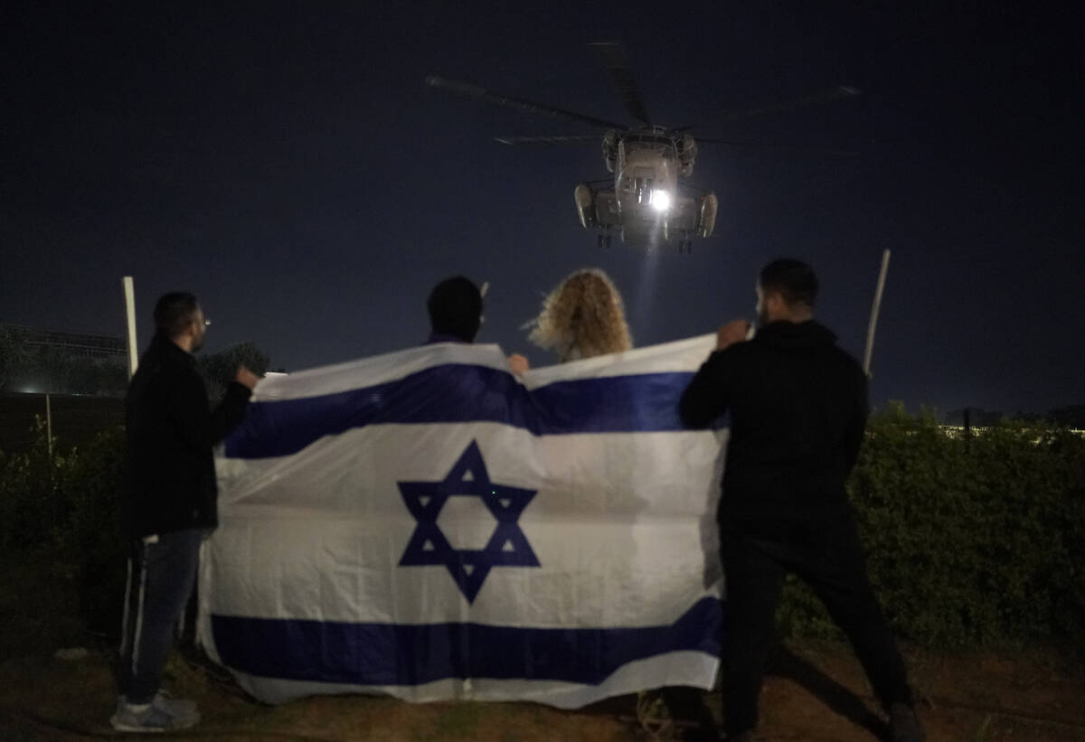 CAPTION CORRECTION CORRECTS LOCATION: People holding an Israeli flag watch the arrival of a hel ...