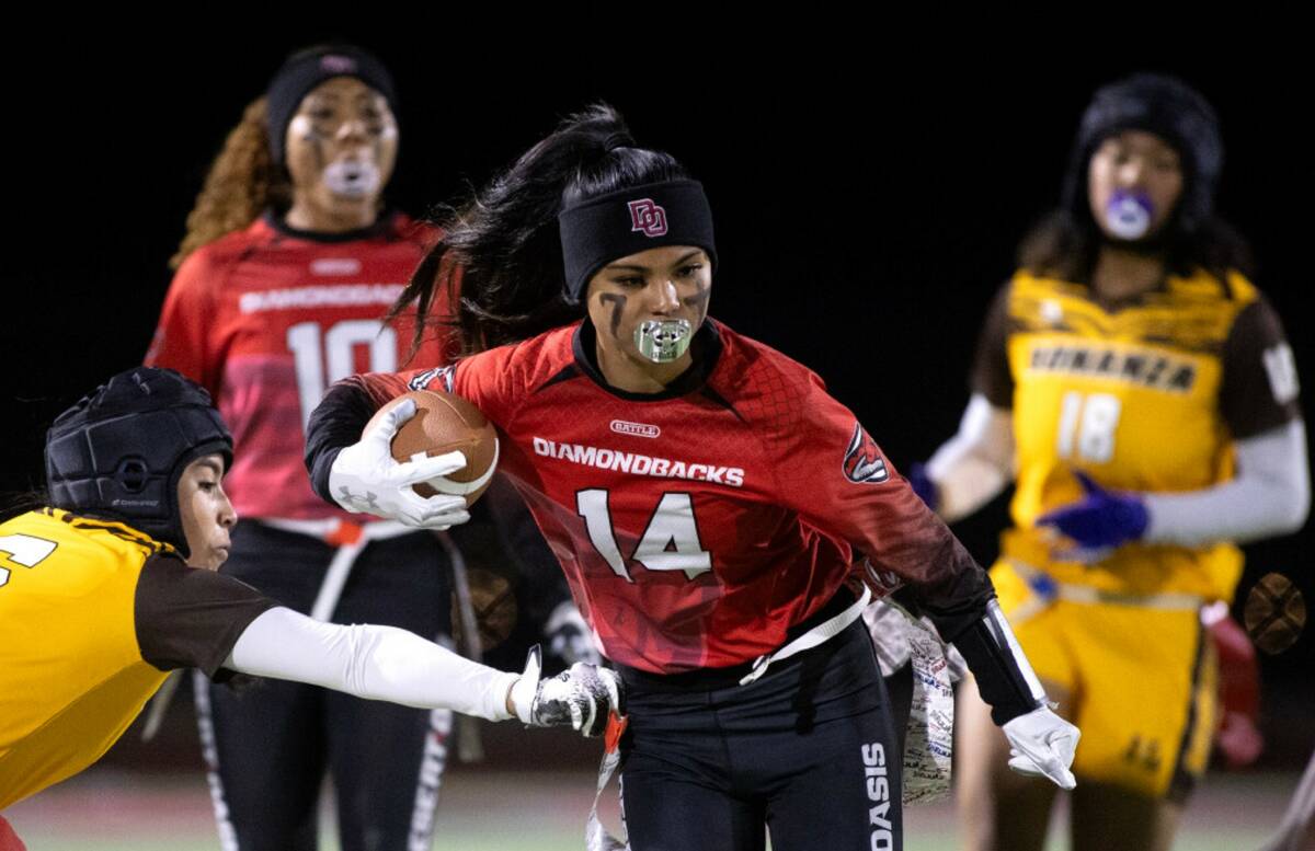 Desert Oasis’ Allie Peralta (14) runs the ball while Bonanza’s Larein Caballero (6) grabs h ...