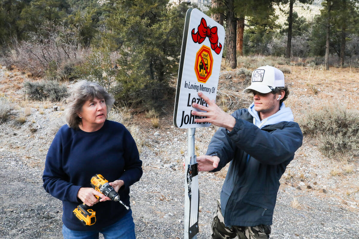Bonnie Heverly and John Bates help put up signs displaying the names of victims who have lost t ...