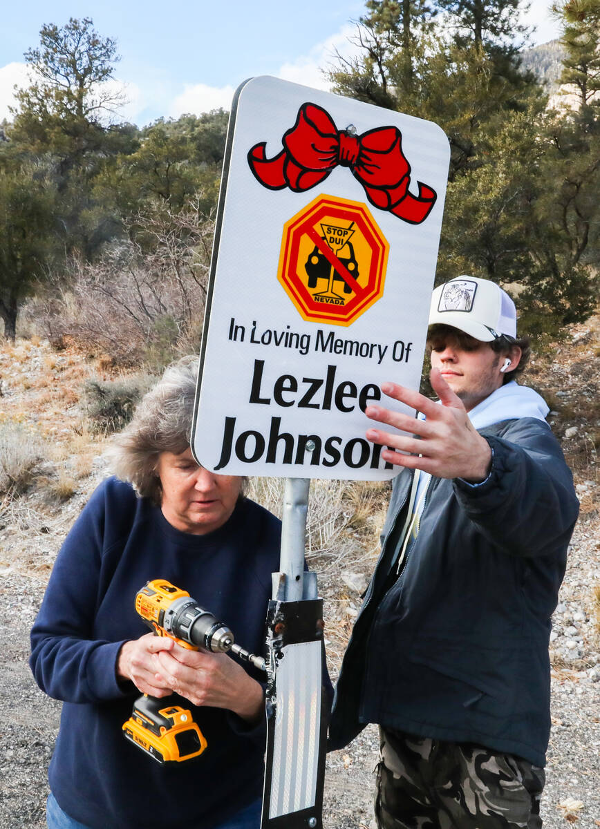 Bonnie Heverly and John Bates help put up signs displaying the names of victims who have lost t ...