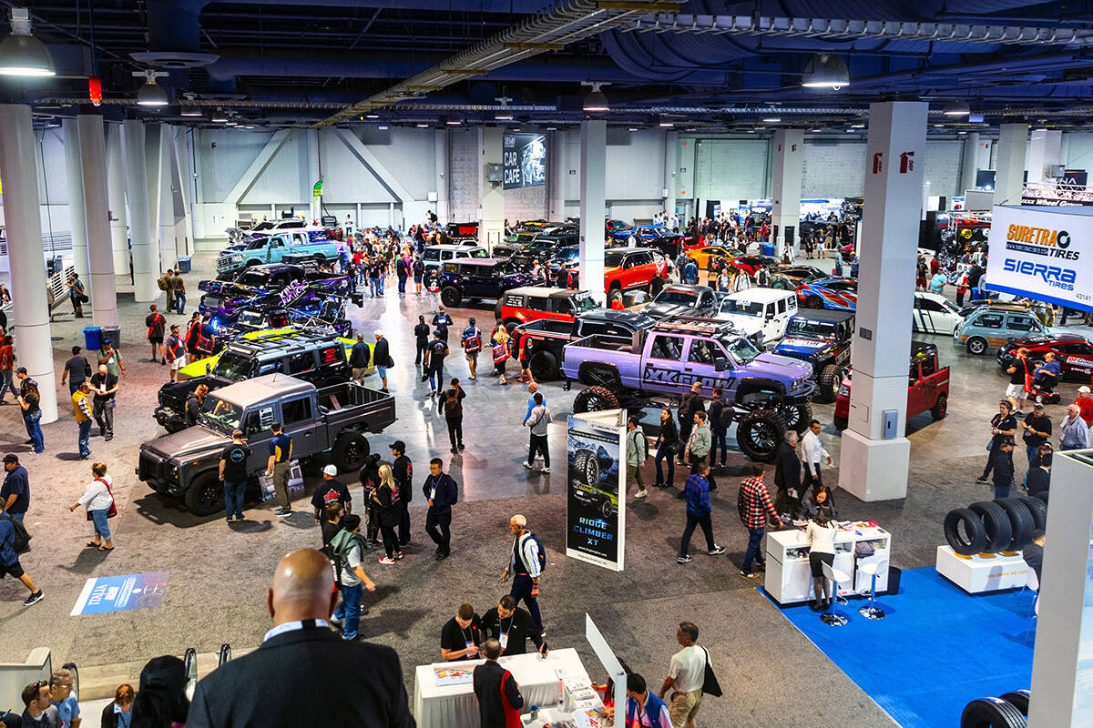 Attendees move about some of the custom vehicles on display during the first day of SEMA at the ...