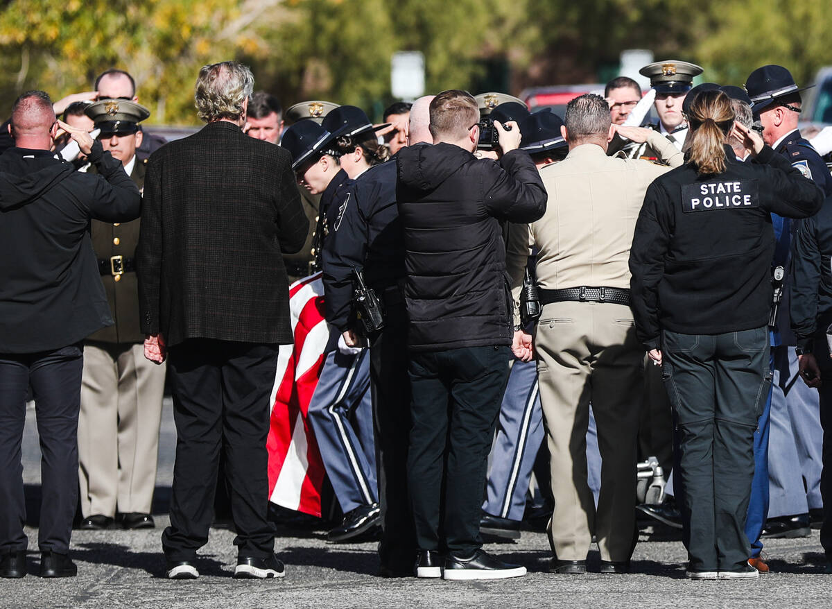 Police salute as the body of a slain Nevada Highway Patrol Trooper is led into the coroner&#x20 ...