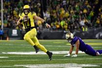 Oregon quarterback Bo Nix (10) eludes the tackle of Washington defensive lineman Voi Tunuufi (9 ...