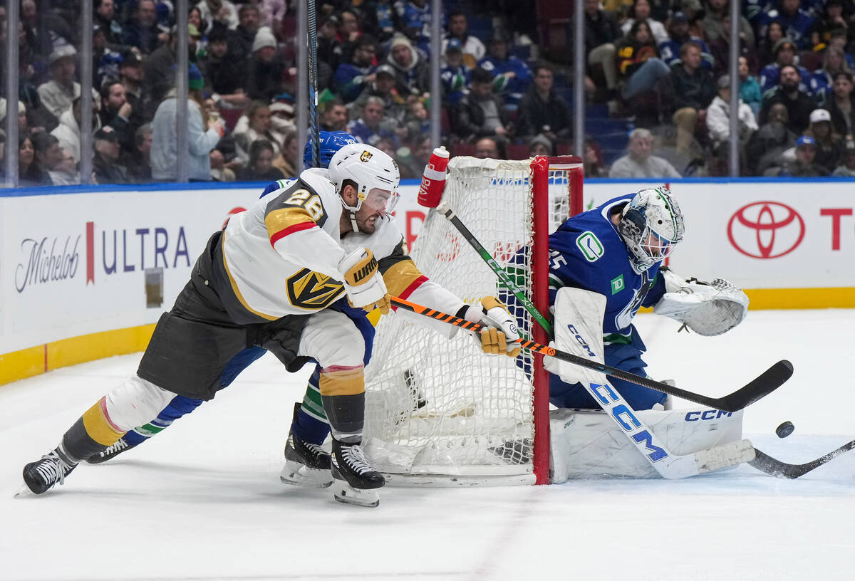Vegas Golden Knights' William Carrier, left, passes the puck next to Vancouver Canucks goalie T ...