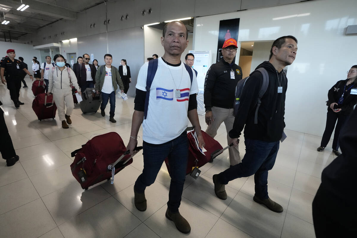 A Thai man wearing a shirt with the Israeli flag, left, and a Thai flag arrives at Suvarnabhumi ...