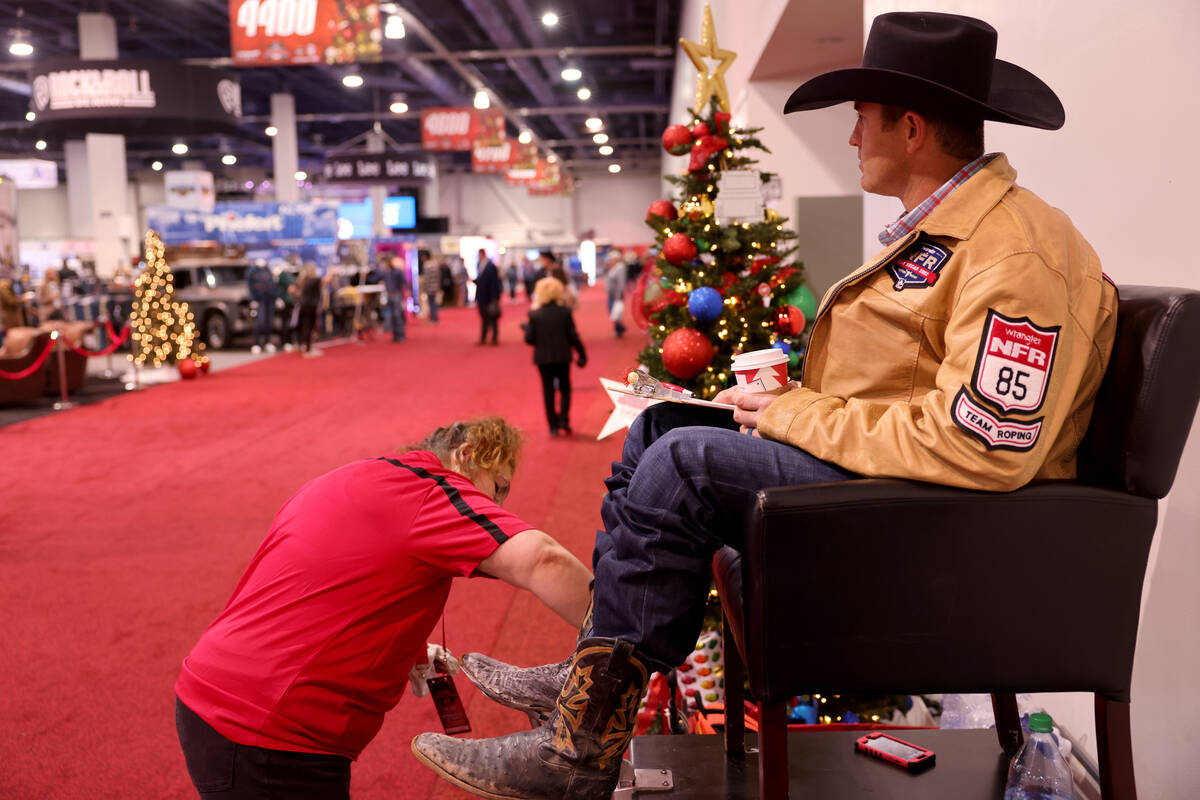 Team roper Rhen Richard gets his boots shines by Mia Asturi during Cowboy Christmas at the Las ...