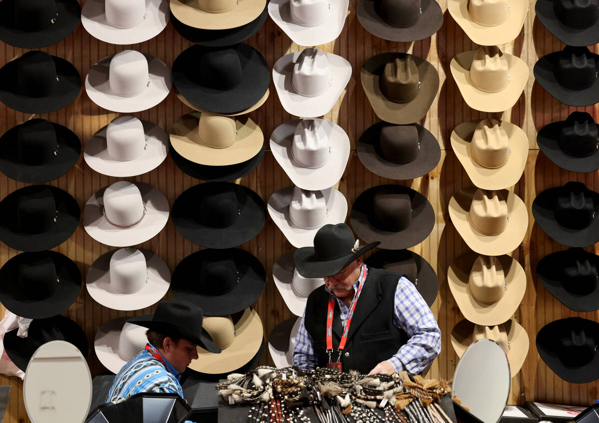 Rick Bishop, right, co-owner of Western Tradition hats and hat accessories, works at his booth ...