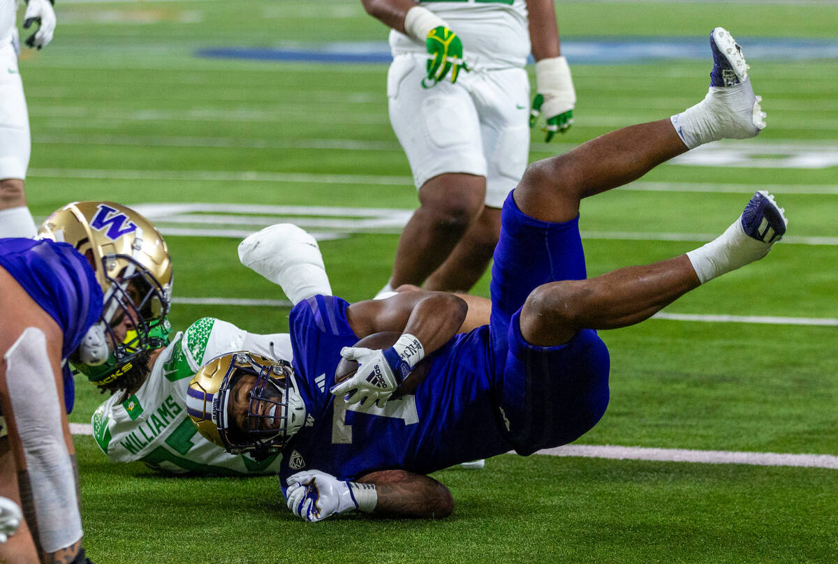 Washington Huskies running back Dillon Johnson (7) falls over Oregon Ducks defensive back Evan ...