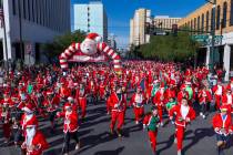 Participants in the 5K run leave the starting line during the Las Vegas Great Santa Run through ...