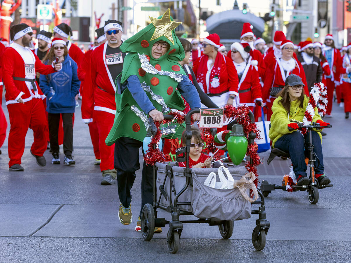 Participants walk to the starting line during the Las Vegas Great Santa Run through downtown on ...