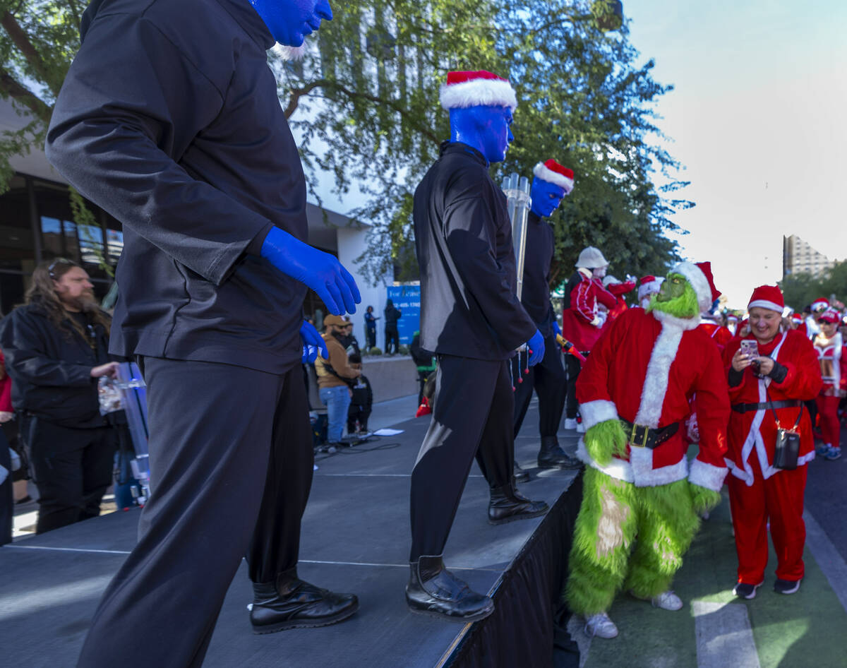 A grinch looks to the Blue Man Group at the starting line during the Las Vegas Great Santa Run ...