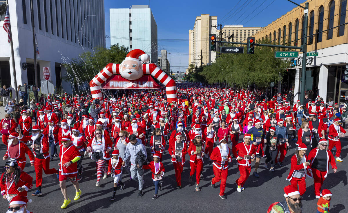 Participants in the 5K run leave the starting line during the Las Vegas Great Santa Run through ...