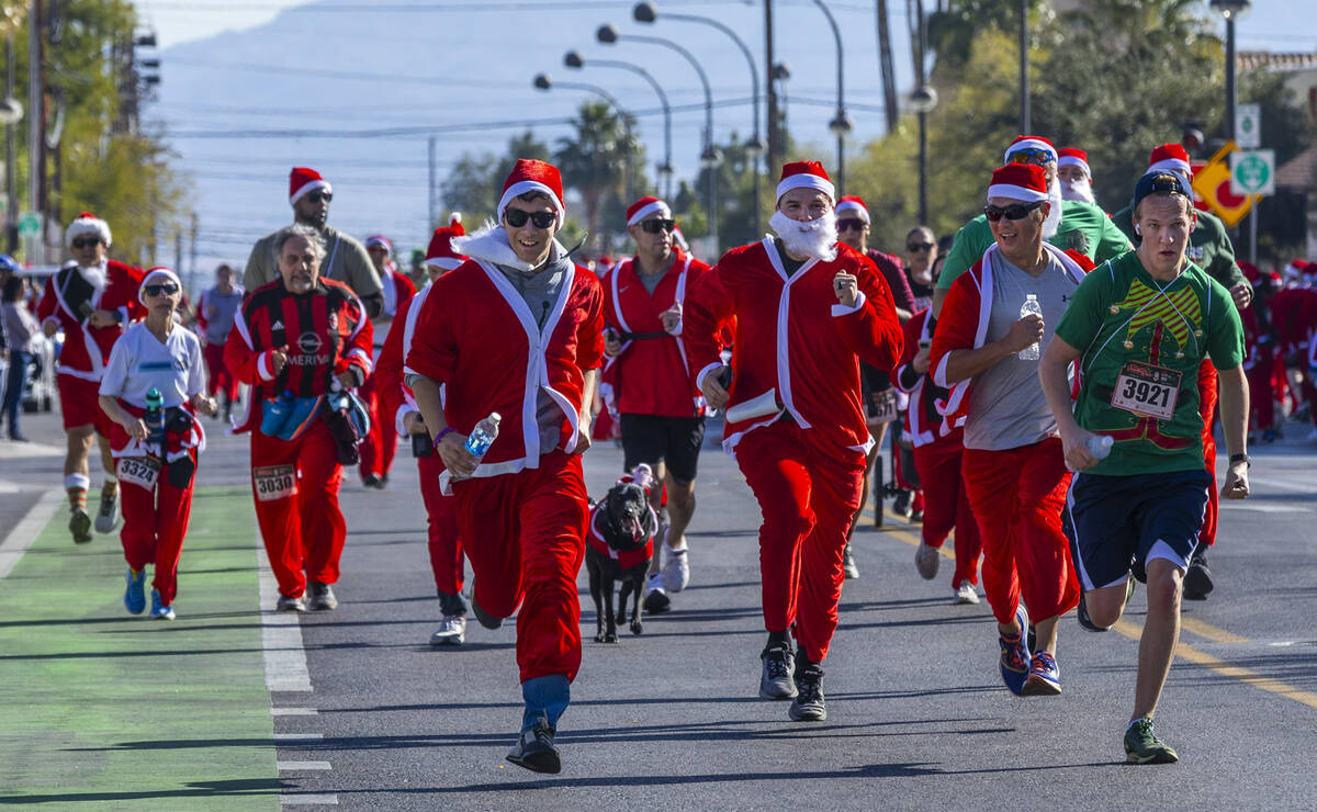 Participants in the 5K run race to the finish line during the Las Vegas Great Santa Run through ...