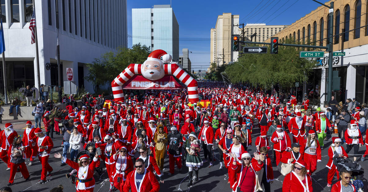 Participants in the 5K run leave the starting line during the Las Vegas Great Santa Run through ...