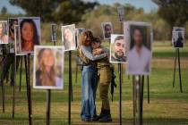 Israelis embrace next to photos of people killed and taken captive by Hamas militants during th ...