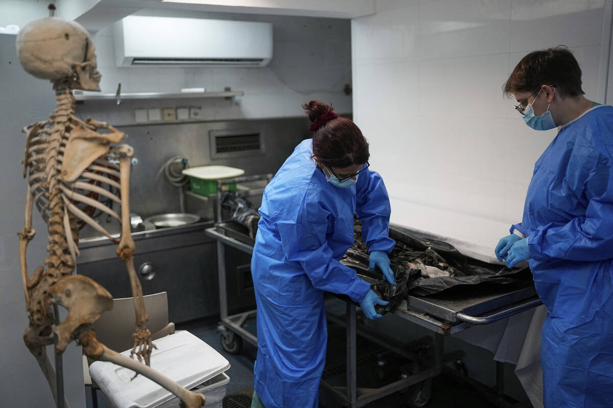 FILE - Israeli forensic experts work on bodies of Israelis killed by Hamas militants in the Nat ...