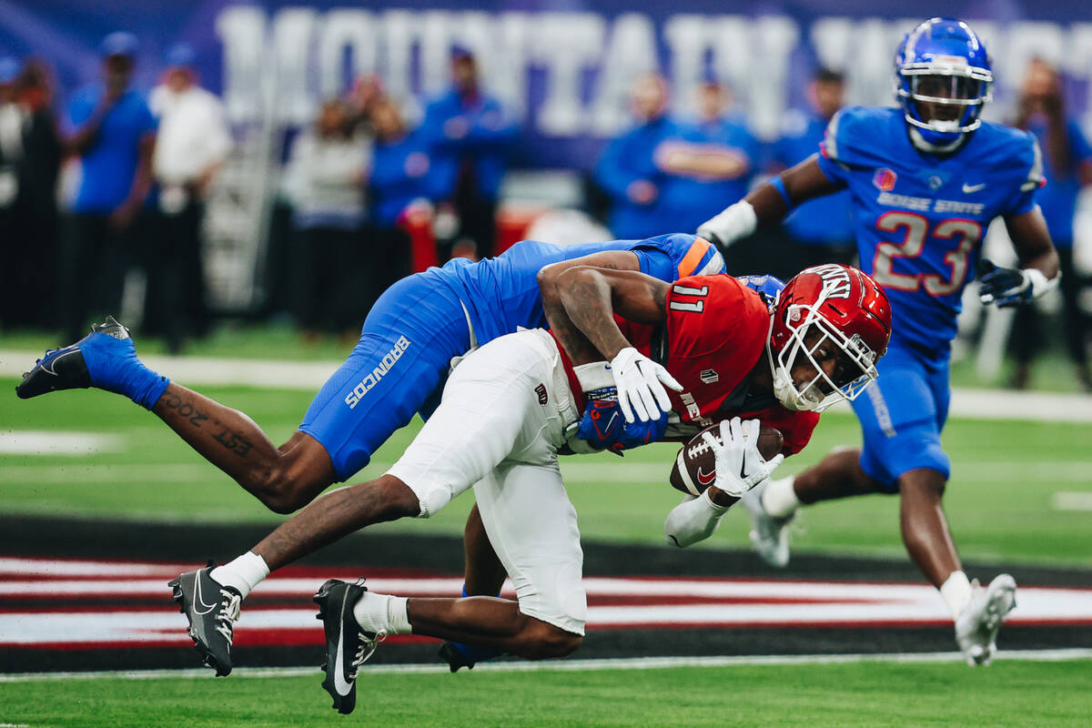 UNLV wide receiver Ricky White (11) gets tackled with the ball by a Boise State defensive playe ...