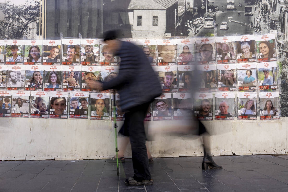 People walk past a wall with photos of the hostages who are believed to remain captive in the G ...